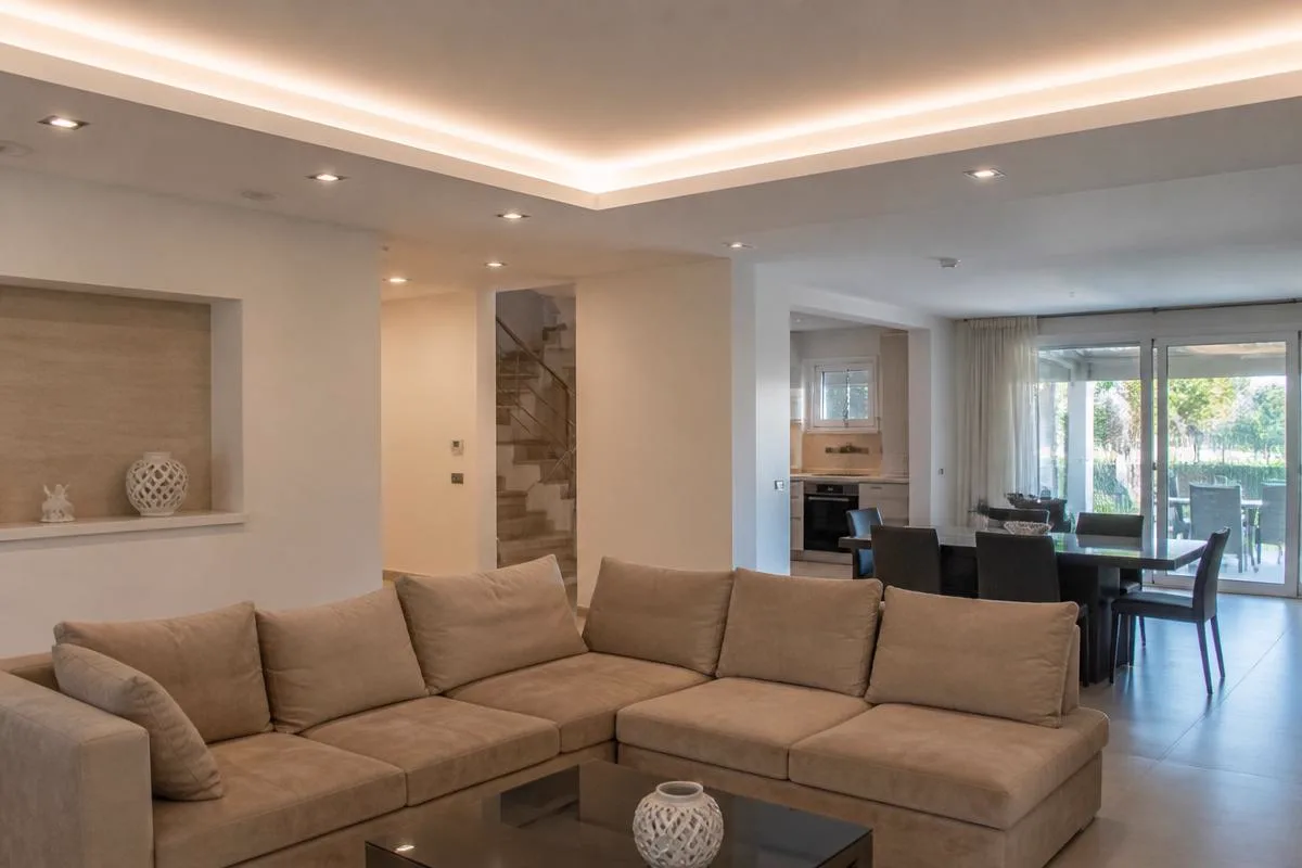 Controsoffitto in cartongesso con faretti e illuminazione integrata in un soggiorno contemporaneo